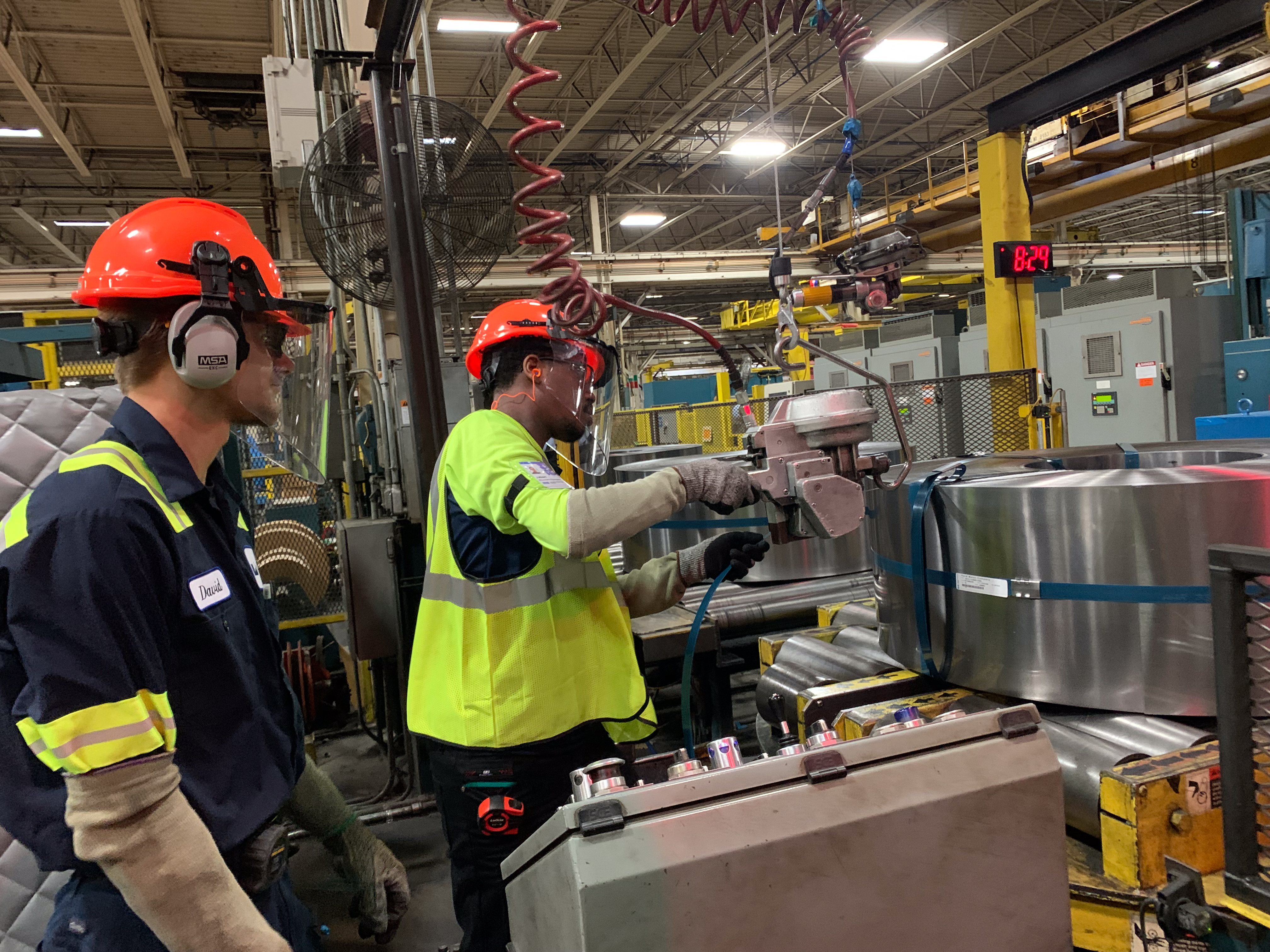 Worthington Steel employees operating coil handling equipment inside a steel processing facility.