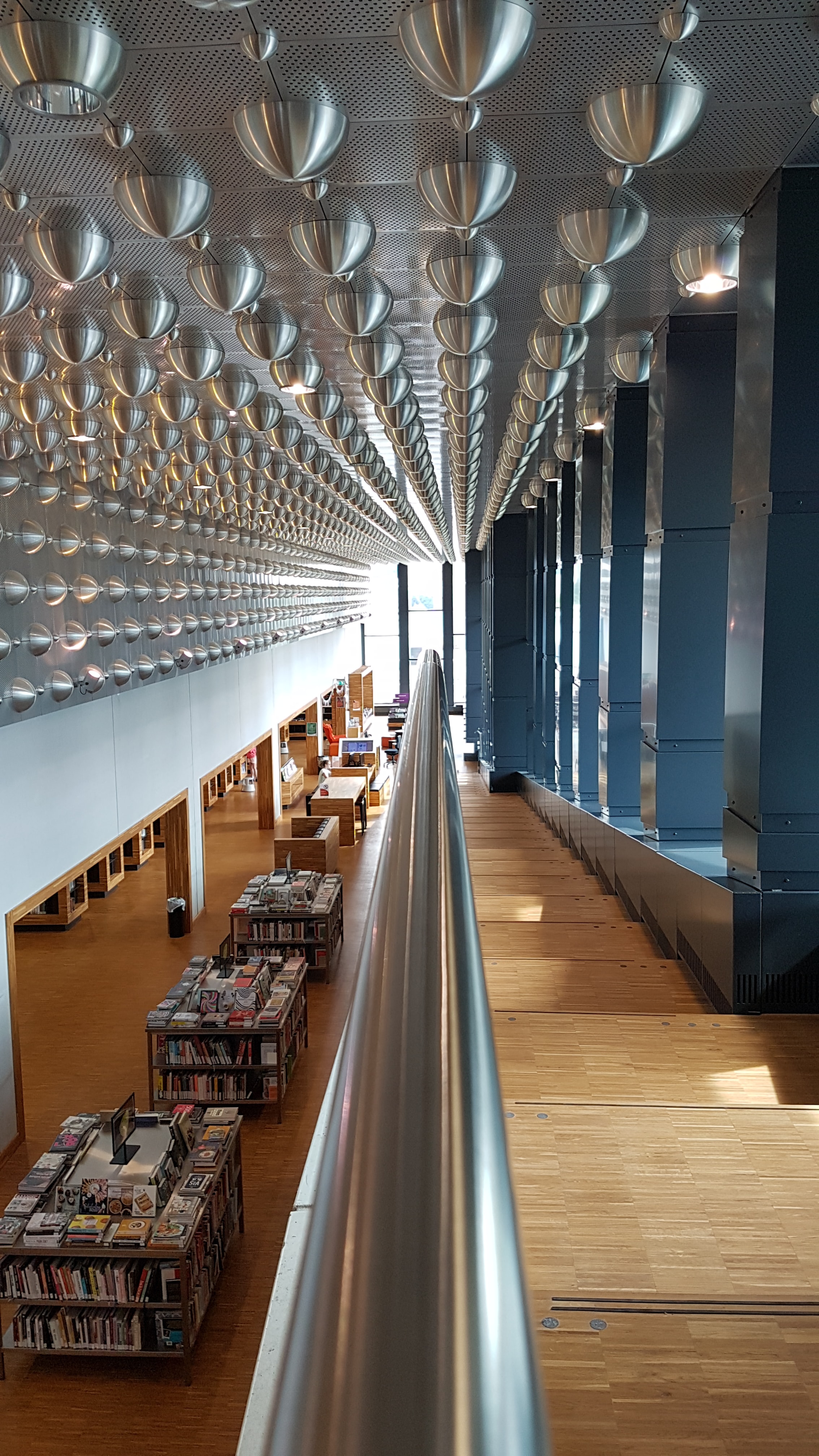 wide angle view of bookstore with wood and steel architecture with steel bar running down staircase