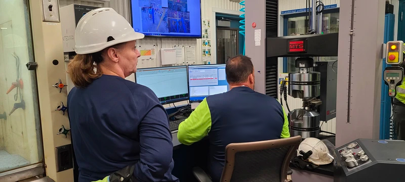 Two employees running tensile test to determine mechanical properties in Worthington lab.