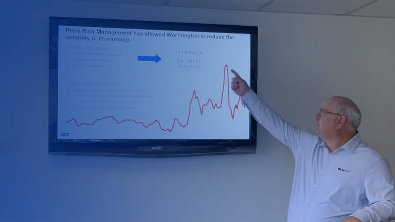 A man pointing at a screen showing a graphic of price for steel.