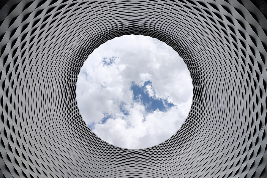 Upward view through a circular steel architectural structure with an open sky above, symbolizing Worthington Steel's commitment to sustainability.