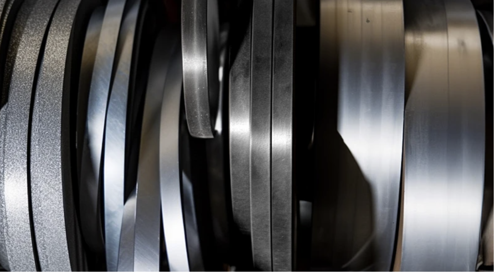 An assortment of slit steel coils with various diameters and surfaces.