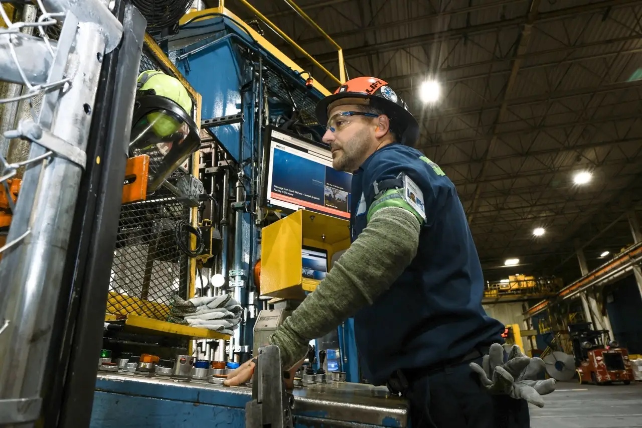 A closeup of a male line employee working on equipment to process steel.