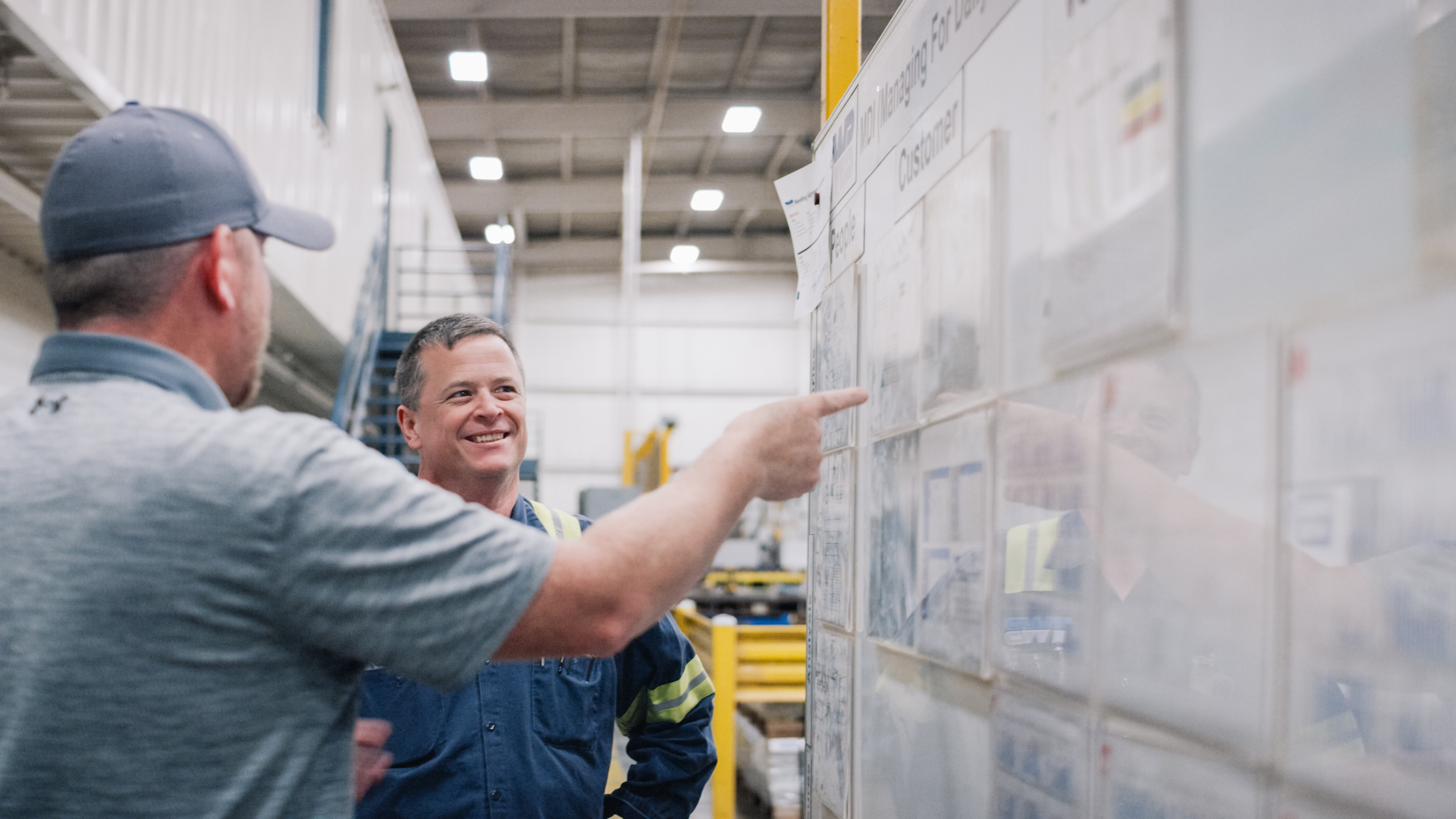 Coworkers smiling together as they look at work board